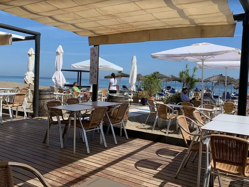 Terraza de madera del Chiringuito África Beach con mesas y sombrillas, frente al mar